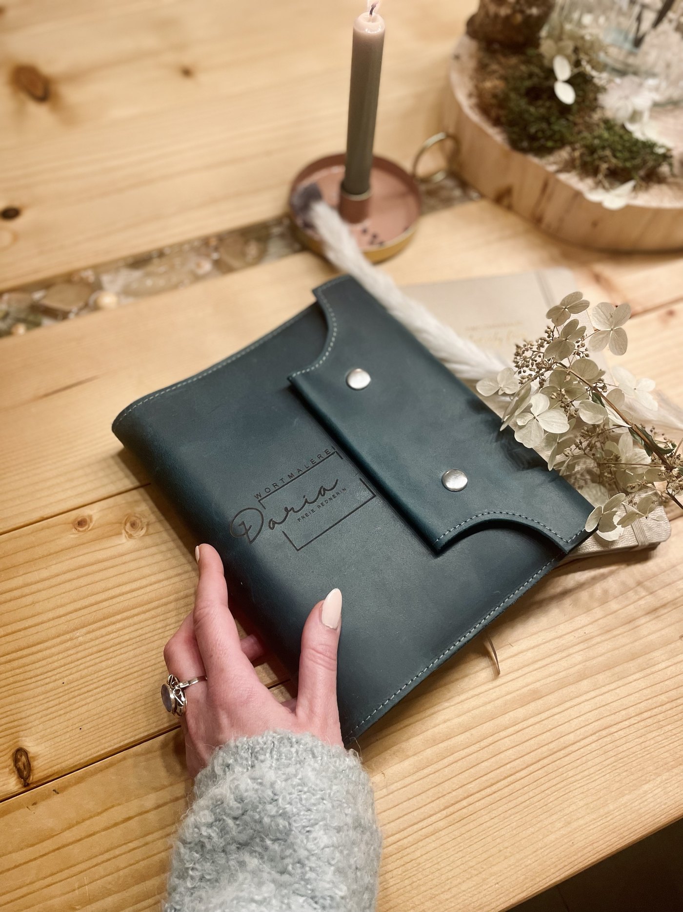 Die Ledermappe mit dem Namen Daria, Freie Rednerin, auf einem Holztisch
