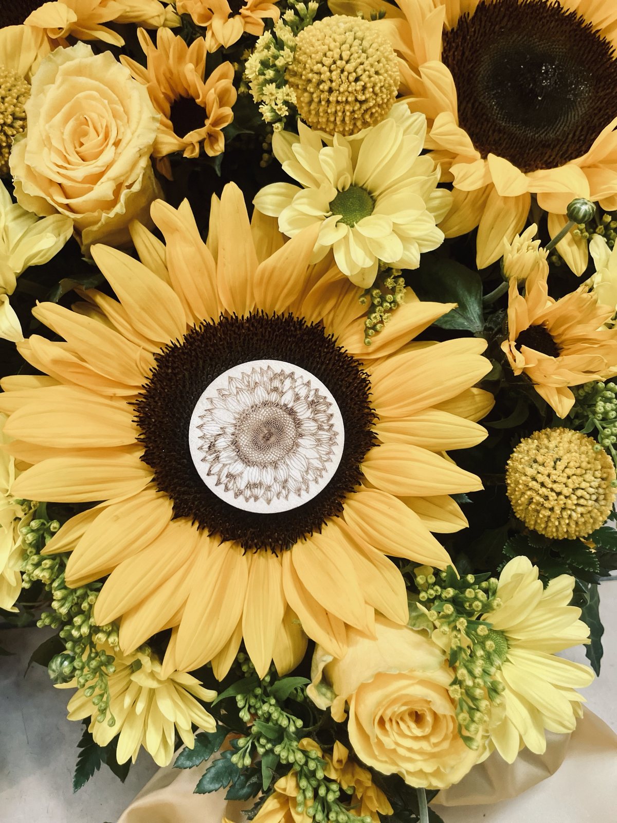 Sonnenblumen bei einer Trauerfeier in der neuen Halle auf dem Mülheimer Hauptfriedhof, in der Mitte eine kleine Holzscheibe mit gravierter Sonnenblume